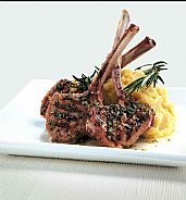 three pieces of lamb crusted on bed of mushed potatoes and rosemary on white plate