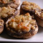 Several mushrooms topped with filling and baked on a plate