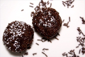 Two chocolate truffles with chocolate bits around them.