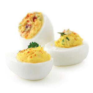 Three halves of boiled stuffed eggs with herb and chilli toppings