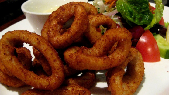 Fried calamari rings on a plate with side salad.