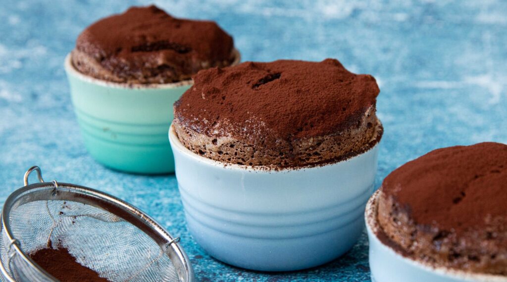 3 dessert souffles dusted with cocoa powder on blue background
