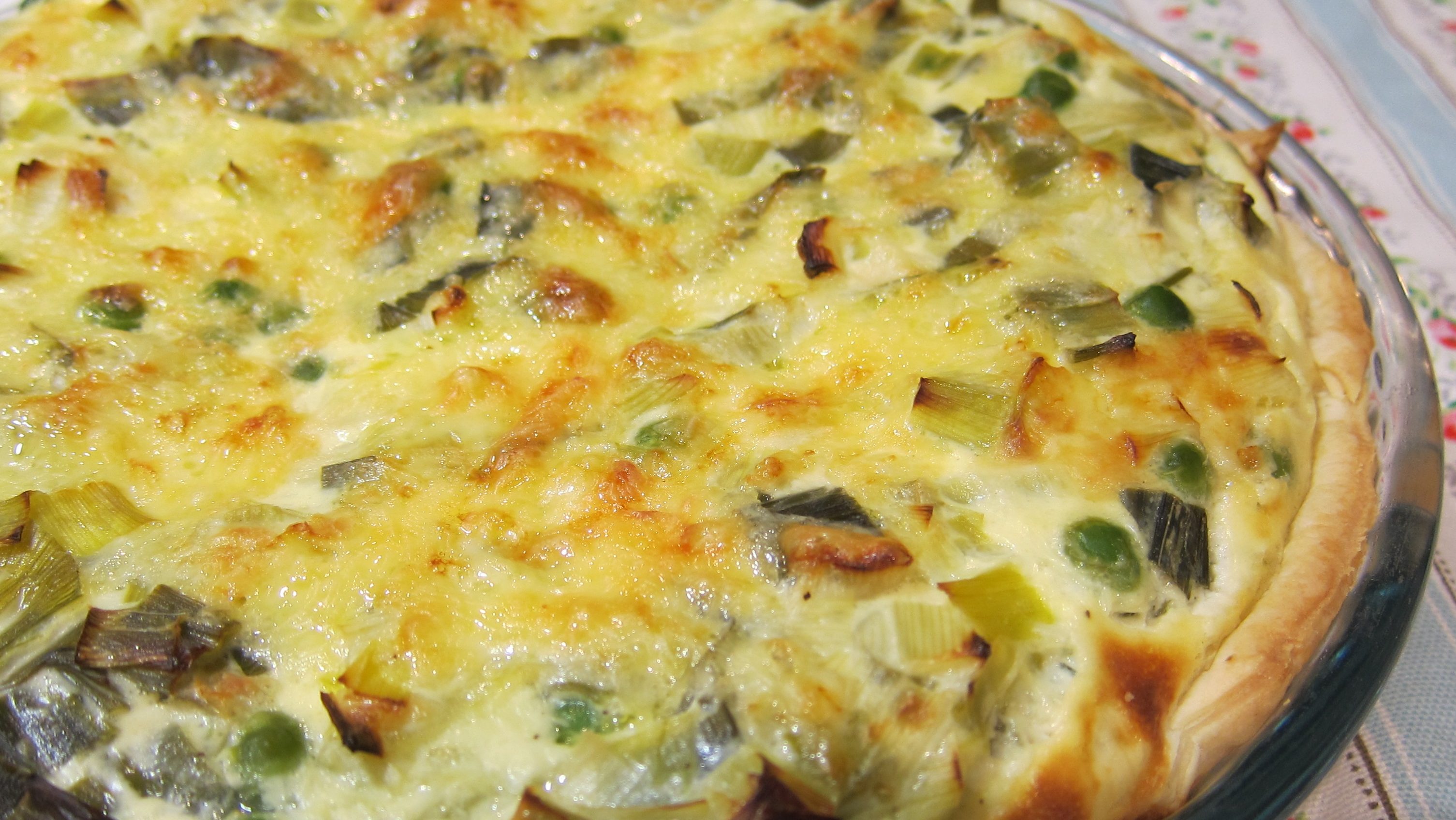 A round quiche with green vegetables bits showing.
