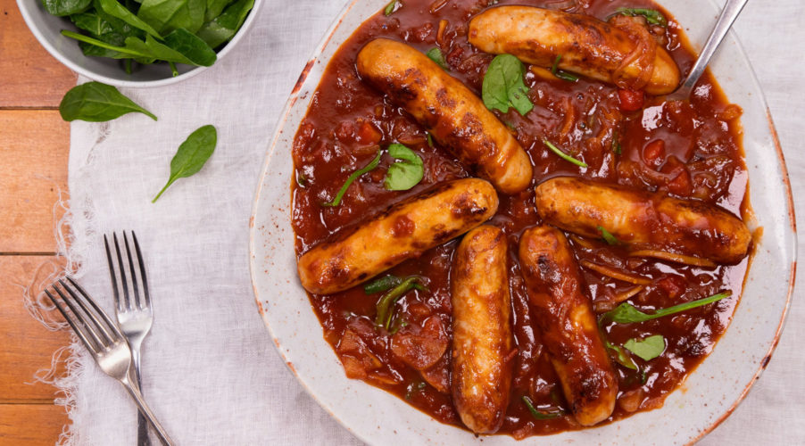 6 devilled sausages in tomato sauce in a large round bowl.