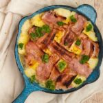 A bacon lattice top pie in blue skillet on white cloth