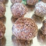 Several cocoa balls dusted with white sugar lined up.