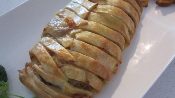 Baked wrapped pie on white platter.