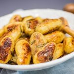several roast baby potatoes heaped in a white bowl.