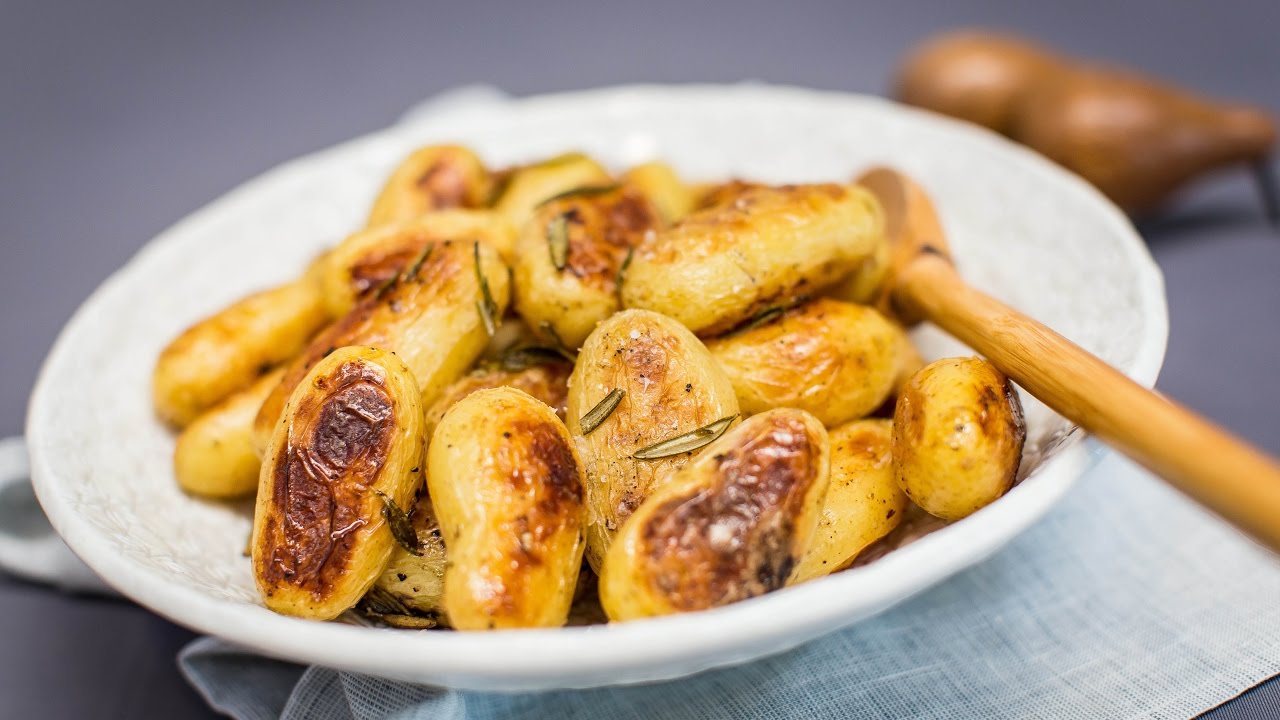 several roast baby potatoes heaped in a white bowl.