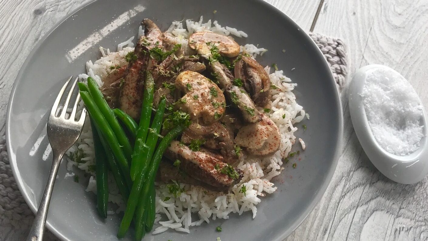 Beef and mushroom stroganoff on white rice with asparagus on grey round plate.