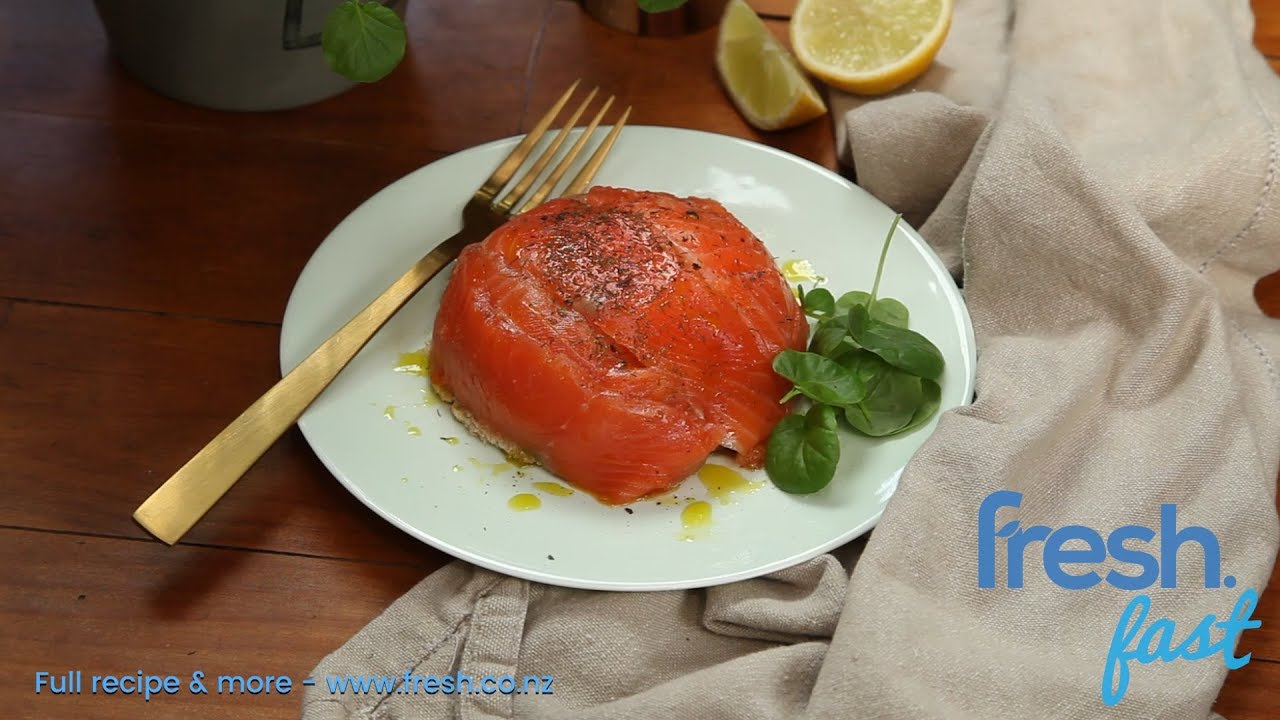 A smoked salmon dome shaped food on a plate with fork and herb.