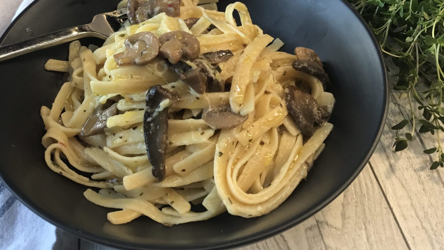 A bowl of pasta topped with mushrooms.