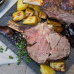 Whole rack of beef rib roasted and a few sliced with potatoes and herb,