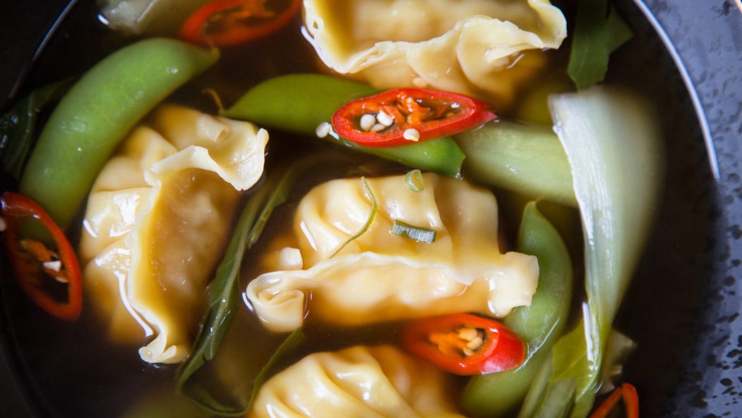 Four dumplings, spring onions and chilli in brown clear soup