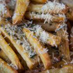 Close up of potato fries covered with grated Parmesan cheese