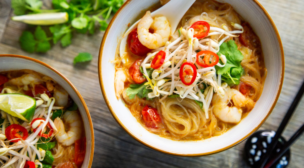 Two bowls of noodle soup woth prawns, sprouts, green and chilli