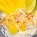 A bowl of white rice pudding topped with yellow fruit pieces and coconut.