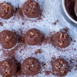 12 chocolate balls and a bowl of cocoa on white paper