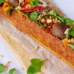 Long french stick sandwich filled with meatballs and vegetables.