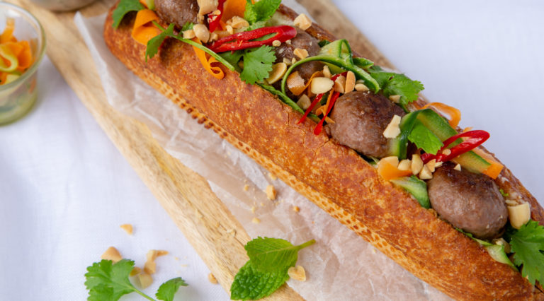 Long french stick sandwich filled with meatballs and vegetables.
