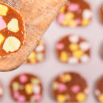 Slices of colourful lolly cakes in the background, one slice on a wooden spatula close up in front