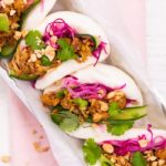 Four bao buns filled with colourful ingredients on a tray