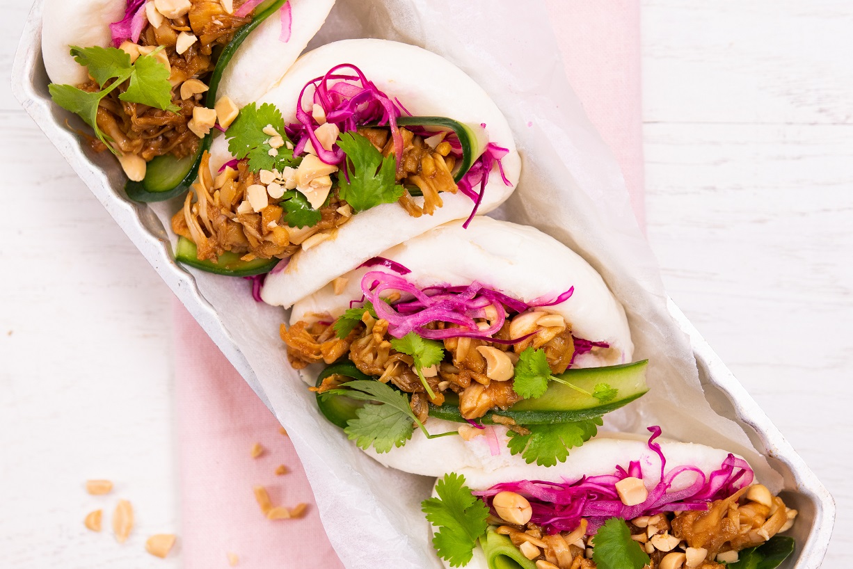 Four bao buns filled with colourful ingredients on a tray