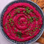 pink dip in a bowl with pita chips