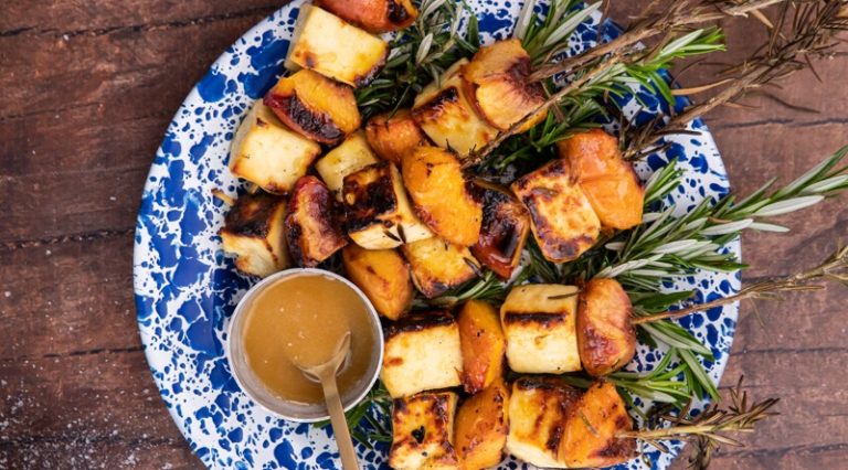 grilled cheese and peach skewers on blue plate and a pot of honey