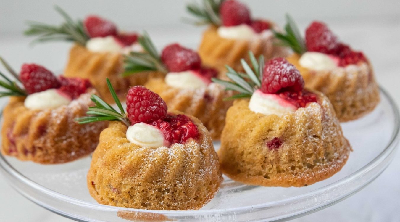 7 cakes with cream and red berries on a glass plate