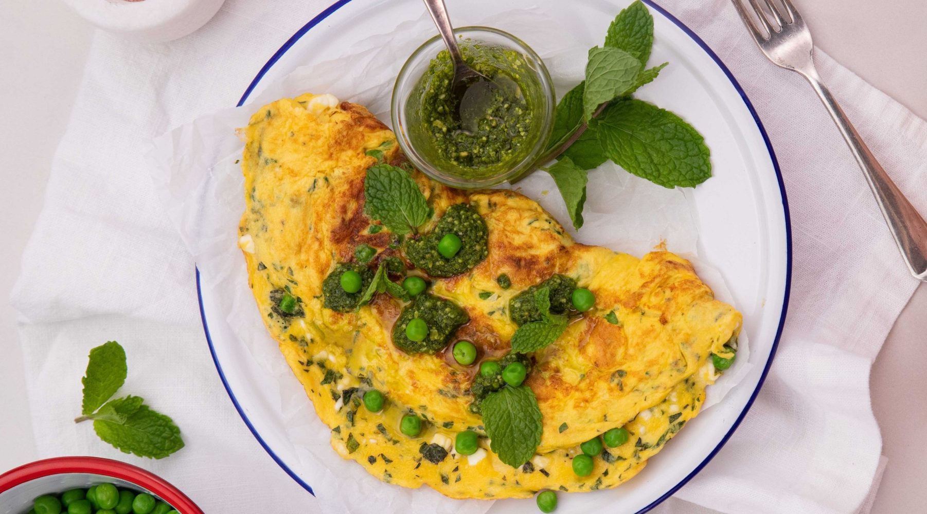 Omelette with green leaves and peas on a round white plate