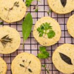 Round biscuits topped with herbs on wire rack
