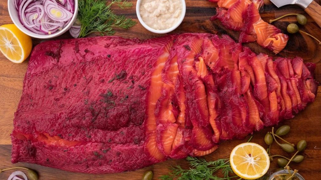 Red flesh fish whole side on a wooden board with lemons, pots and herbs