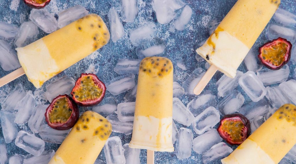 5 yellow and white ice blocks and passionfruit halves on ice cubes