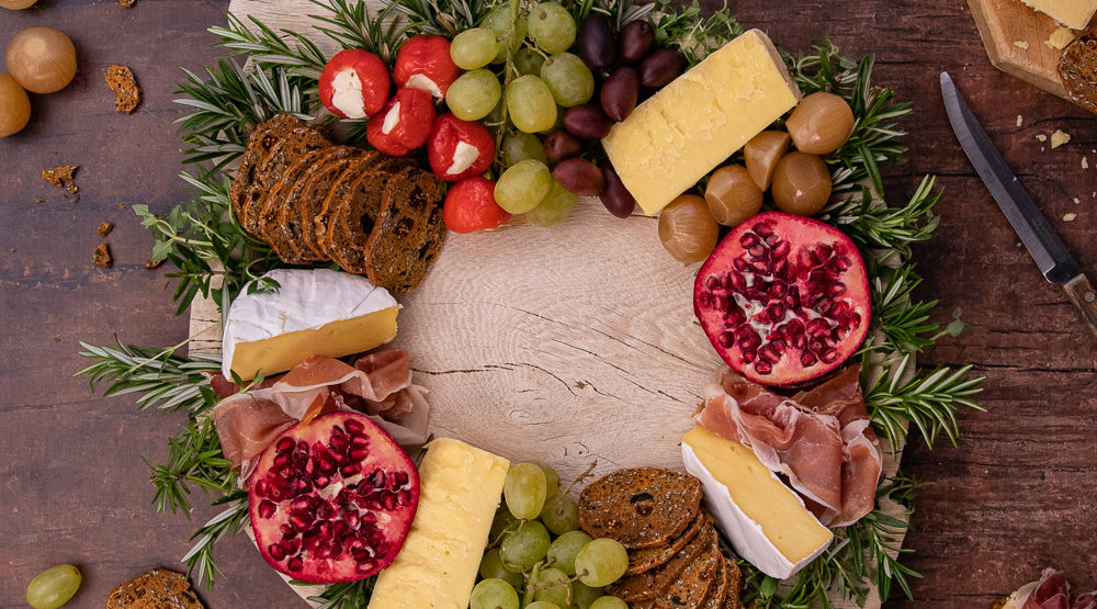 cheese, crackers and fruits placed in a ring on a wooden board