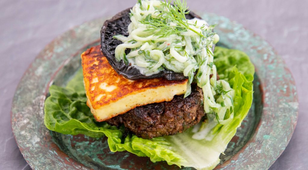 Burger , haloumi cheese,mushroom and white vege salad on a piece of lettuce on rustic plate