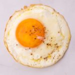 One fried egg on white marble bench top