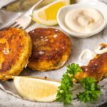 Fish cakes on a plate with lemon wedges, parsley and tartar sauce on a plate