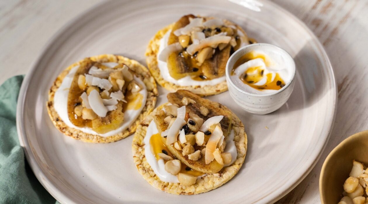 Three Corn Thins crackers with sweet toppings of baked nuts and maple syrup on coconut yoghurt and a side of passionfruit syrup