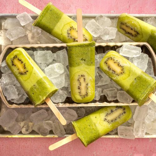 Green rectangle popsicles on cubes of ice on a tray.