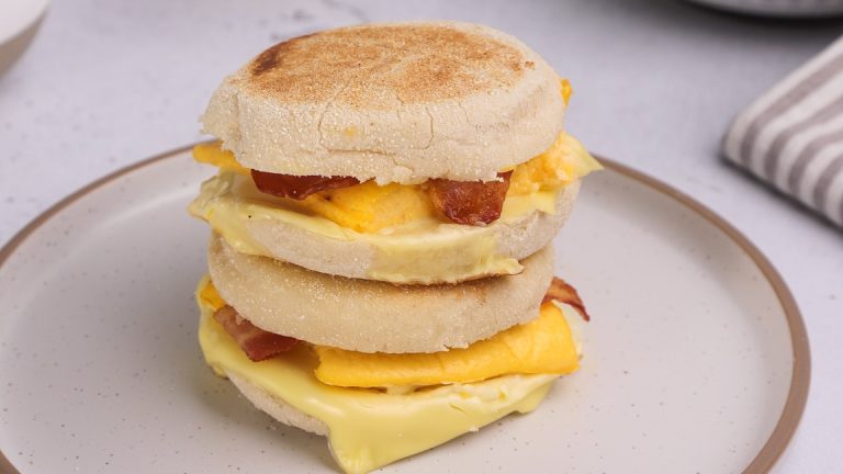 Two English muffin sandwiches stacked on a plate.