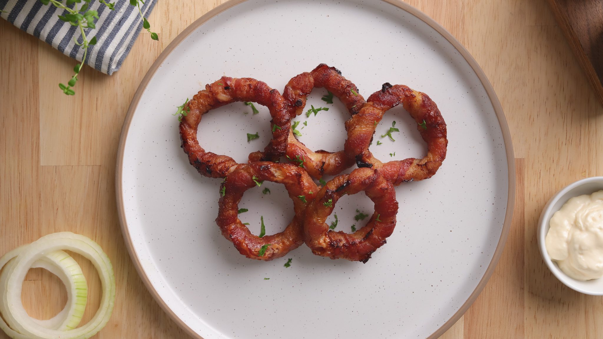 Five cooked onion rings arranged like Olympic logo on a plate.