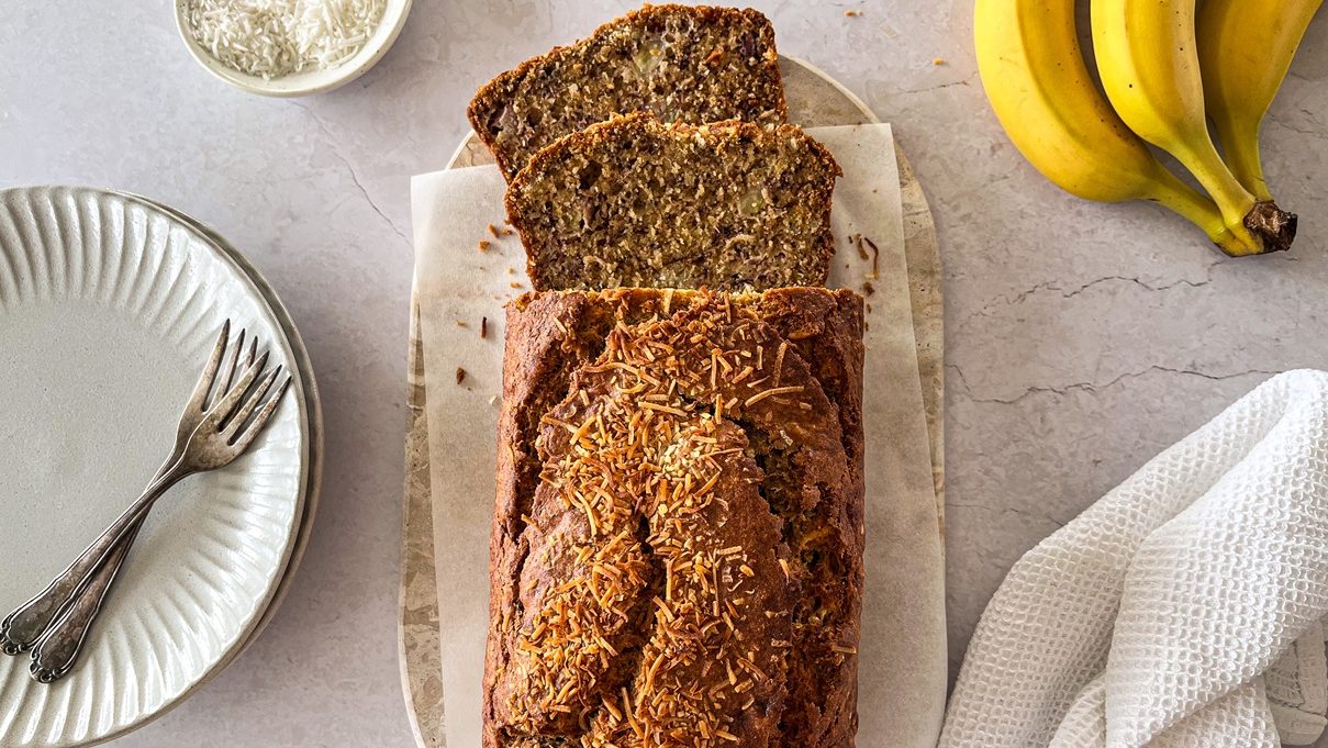 Banana loaf with coconuts on top, with bananas