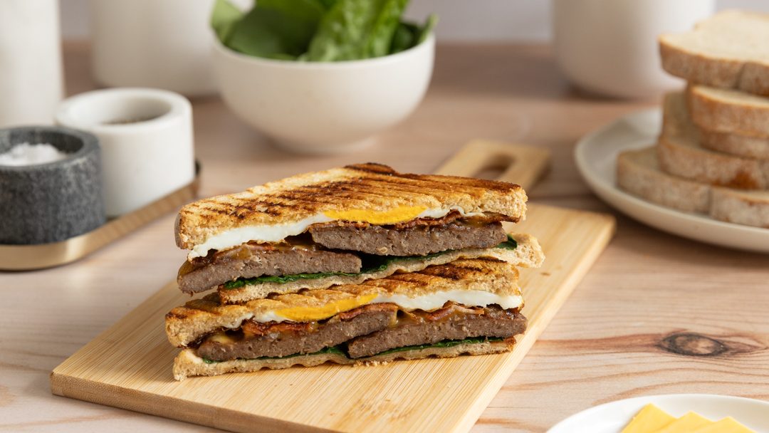 Two slices of toasted sandwich stacked on a wooden board.