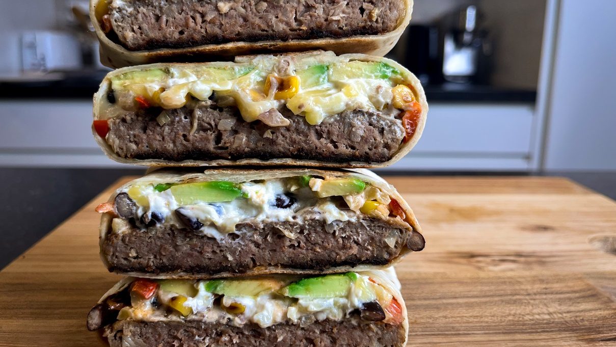 Four burger and salsa wraps stack cut side showing inside on wooden board.