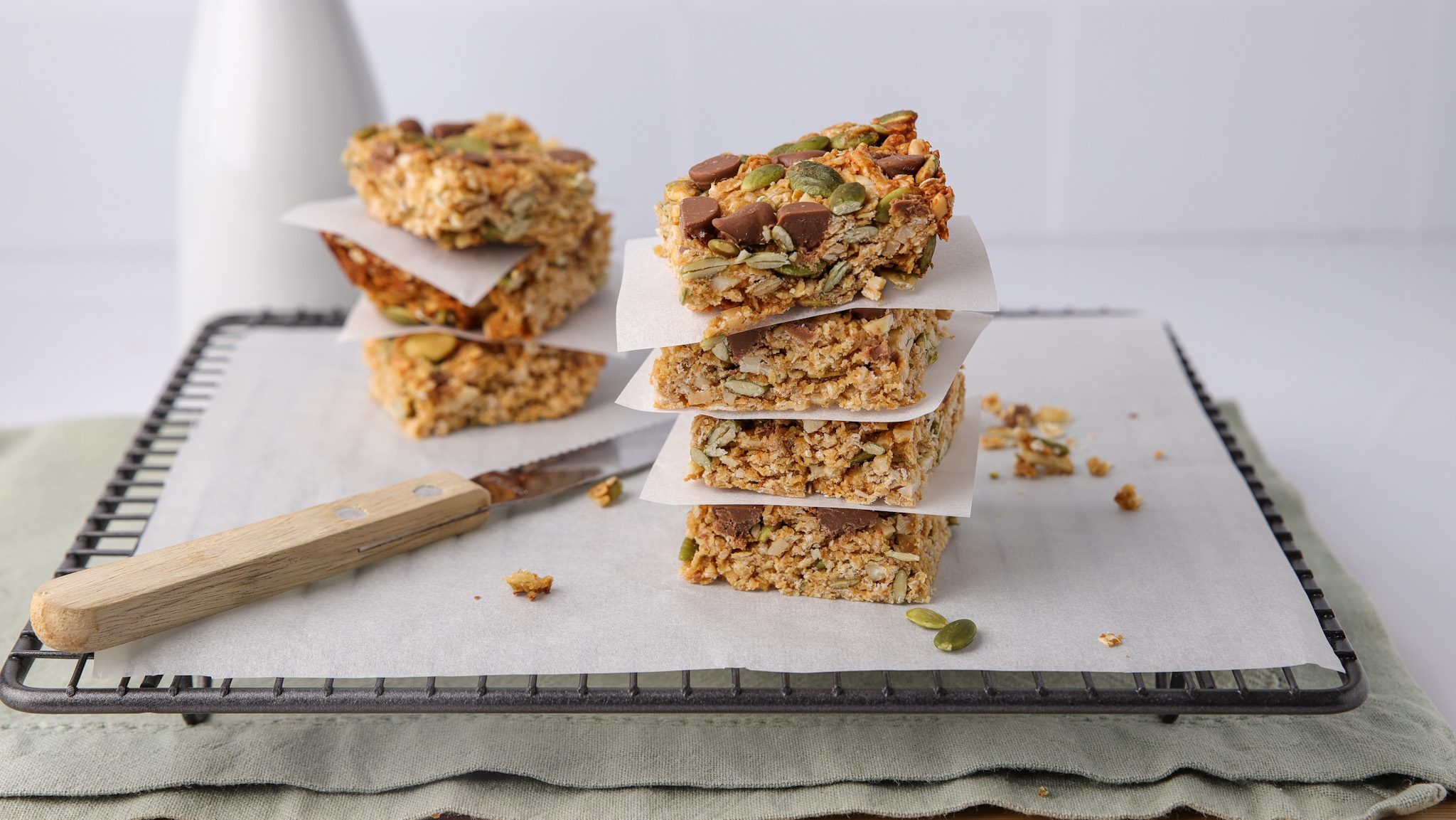 Stacks of muesli bars on paper lined wire rack on kitchen bench.