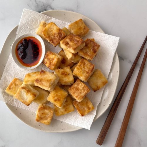 Crispy fried cubed foods on paper towel lined plate with a small bowl of chilli oil. Chopsticks next to it.
