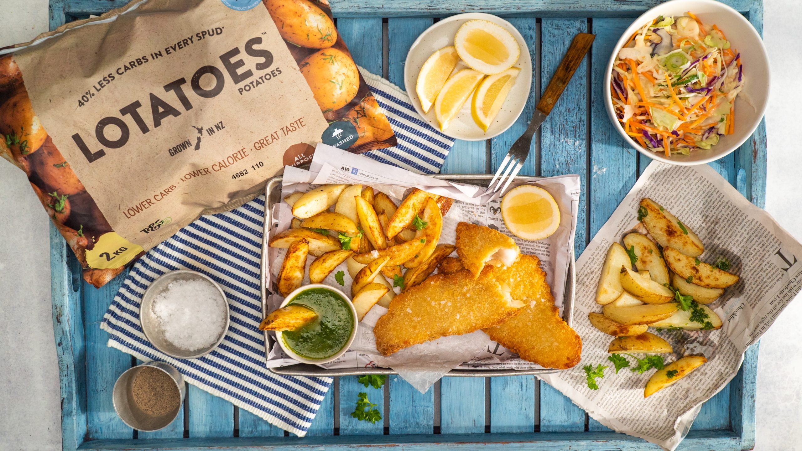 How to make air fryer potato wedges - crumbed fish fillets, potato wedges and herb sauce on a tray with packet of Lotatoes