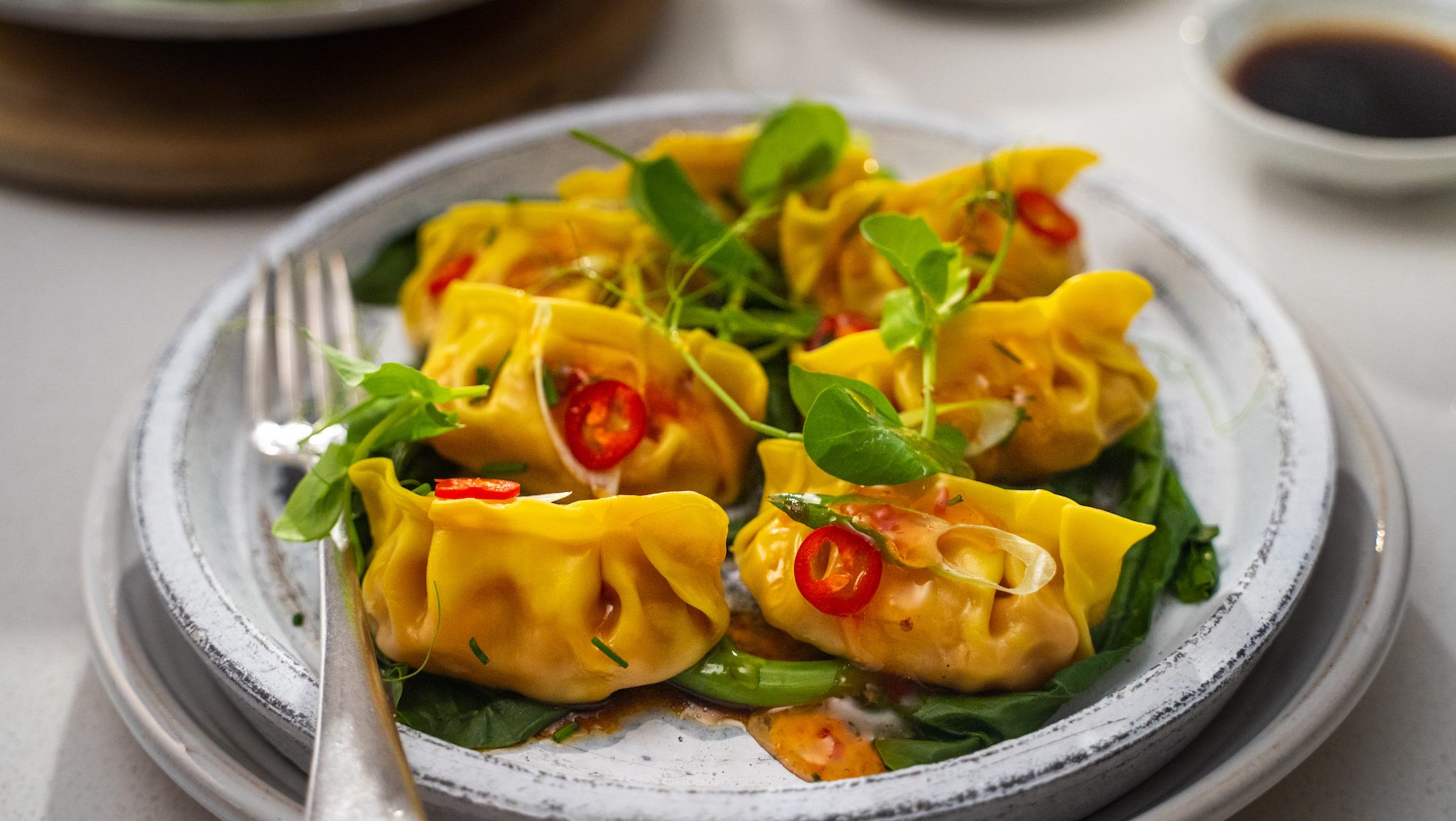 Dim sum - Steamed ginger prawn dumplings on a plate garnished with red chilli slices and fresh herbs