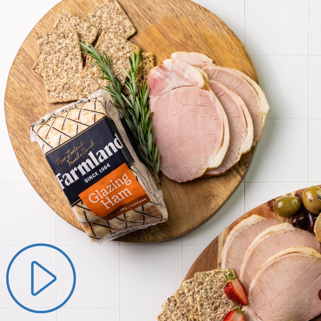Wooden board with whole Farmland Glazing Ham in packet and some slices of ham